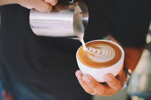 Captivating image of a barista pouring milk art into a cappuccino cup, showcasing latte art skills.