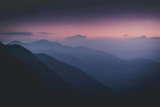 Serene misty mountain range silhouetted against a twilight sky.