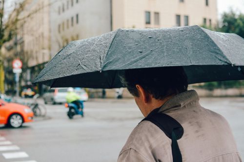 Person walking under an umbrella on a rainy day in Barcelona street.