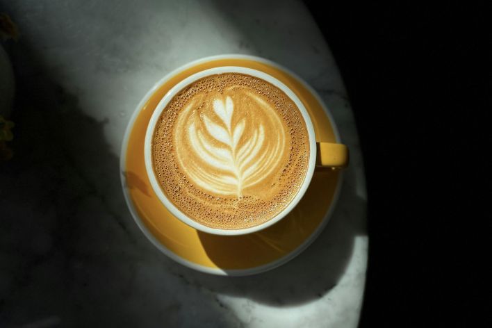 Top view of a beautifully crafted latte with art on a marble table under dramatic lighting.