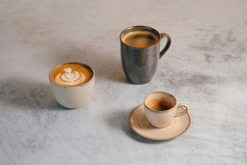 A variety of coffee drinks including espresso, latte art, and mug on a stylish table.